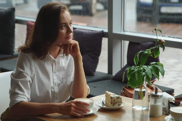 Flickan har en doftande kaffe och söta kaka sitter på ett café. Affärskvinna som vilar under paus — Stockfoto