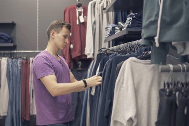 Genç adam giyim mağazası giysilerle arıyor