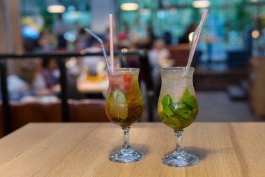 Kokteyl buz cam ve saman ile kapatın. Taze soğuk mojito ahşap bir masaya kokteyl