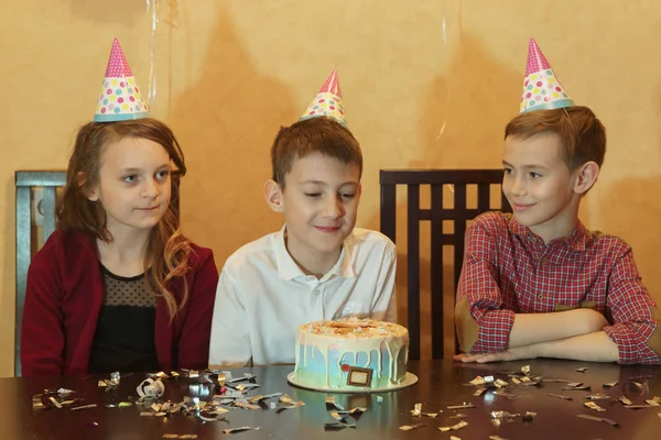 Именинник и его друзья за праздничным столом. праздничный торт на детской вечеринке — стоковое фото