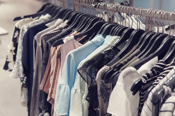 Colorful used blouses on hangers at shopping mall — Stock Photo, Image