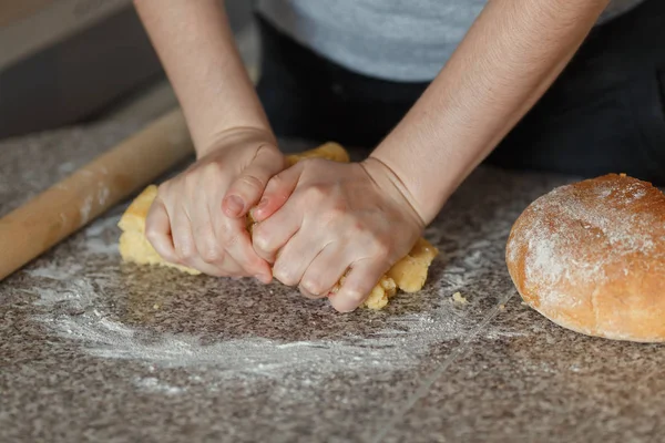 As mãos da menina amassam a massa de farinha na mesa — Fotografia de Stock
