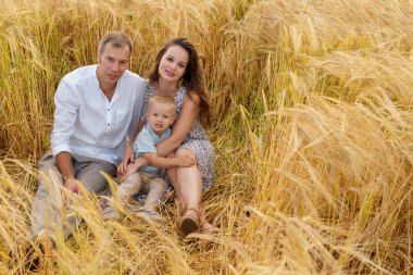 Bir buğday alanında oturuyor ve mutlu bir aile