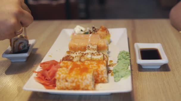 Amigos comiendo rollos de sushi en un restaurante japonés, un bar de sushi. Cena. . — Vídeos de Stock