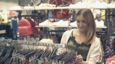 Yeni giysiler seçmek moda alışveriş merkezinde alışveriş genç güzel kadın