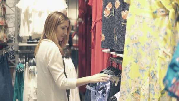 Jonge mooie vrouwen winkelen in fashion mall, het kiezen van nieuwe kleren — Stockvideo