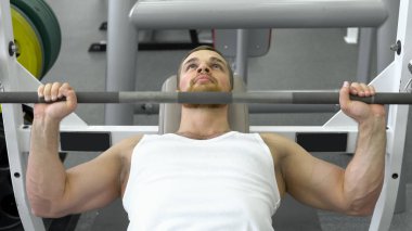 Genç sporcunun fitness kulübünde egzersiz sırasında halter bench basarak yapıyor yerleştirmek. Spor salonunda egzersiz kas adam