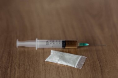 Kokain toz ve ahşap masa üzerinde şırınga ile Plastik paket.