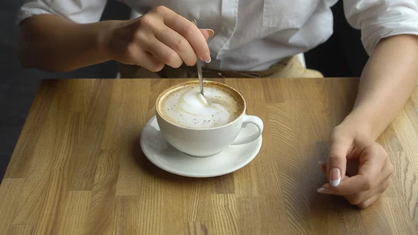 Una joven hermosa mujer bebiendo café en un café. Mano de niña revolviendo azúcar en el café de cerca — Foto de Stock