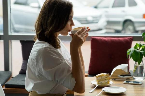 En ung vacker kvinna dricka kaffe på ett café. ung kvinna i business kläder på en lunchrast — Stockfoto