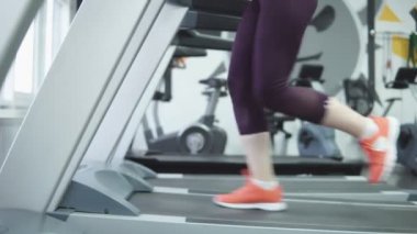 Bir koşu bandı üzerinde çalışan kadın yakın çekim. 4k.