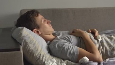 baş ağrısı ile yatakta hasta genç adam