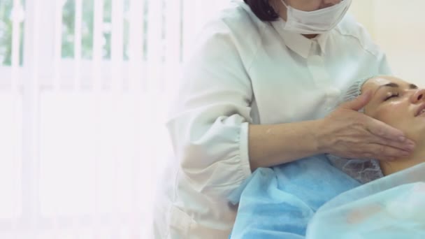 En la recepción con el cosmetólogo - el médico femenino aplica el masaje y el remedio especial para el rejuvenecimiento facial . — Vídeos de Stock