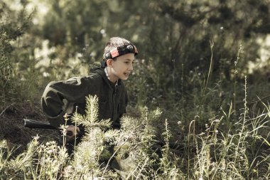 Kamuflaj silahlı bir çocuk vuruyor, lazer etiketi