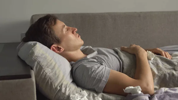 Крупный план больного молодого человека кашляет спать в постели — стоковое фото
