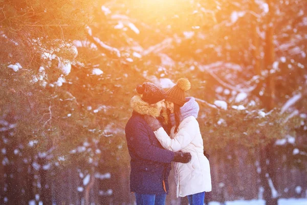 Счастливый молодой человек и женщина обнимаются в зимнем лесу — стоковое фото