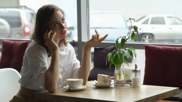 Chica joven bebiendo café y hablando por teléfono móvil en la cafetería. mujer de negocios discusión de asuntos de negocios en la hora del almuerzo —  Fotos de Stock