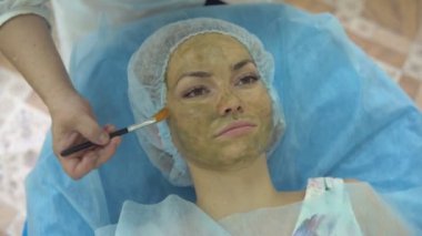 Genç güzel kız kozmetik kliniğinde tedavi anti-aging yüz maskesi uygulaması sırasında.