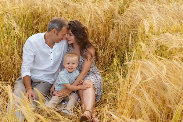 Alegre familia sentada en un trigo en el campo — Foto de Stock
