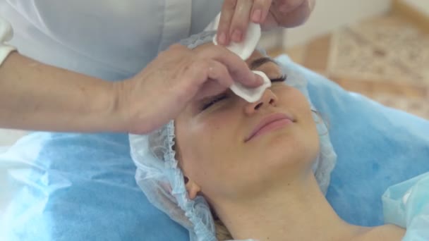 Nahaufnahme eines jungen hübschen Mädchens während eines kosmetischen Eingriffs für das Gesicht, der vom Facharzt durchgeführt wird — Stockvideo