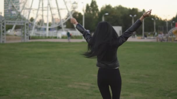Молода весела дівчина в сонячному літньому парку відкриває руки в сторони під час прогулянки в парку — стокове відео