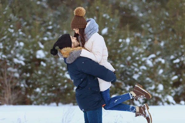 Молодая пара обнимается и целуется в зимнем лесу — стоковое фото