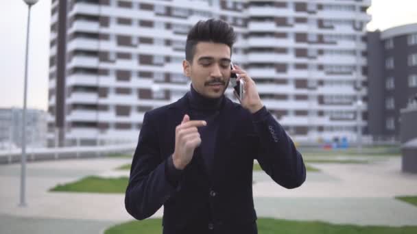 Gelukkig stijlvolle zakenman horen goede nieuws over de telefoon en verheugt zich met gelukkig emoties buiten in de buurt van kantoorgebouw — Stockvideo