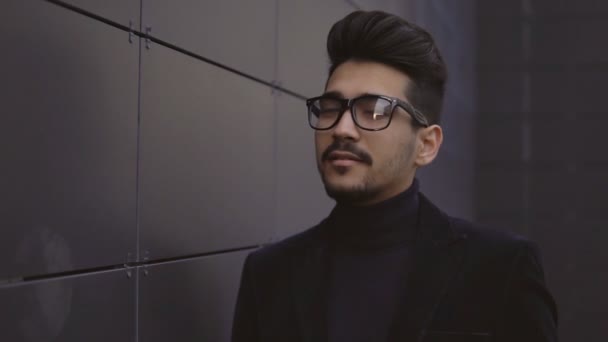 Молодой кавказский бизнесмен в очках в современном центре города с улыбкой на лице — стоковое видео