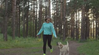 Genç kadın ile köpek ormanda yürüyor
