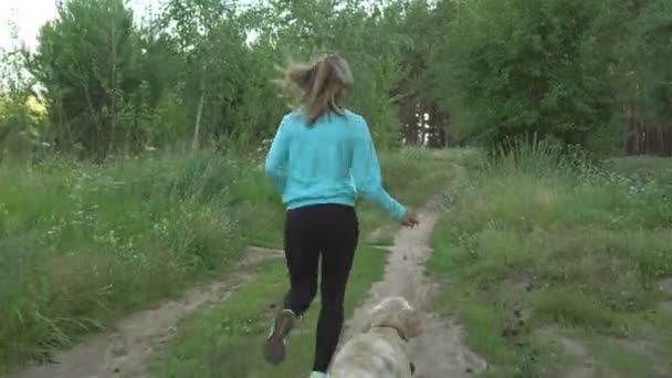 Jovem corre através da floresta com seu cão puro sangue no dia quente de verão . — Vídeo de Stock