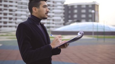 Kalem ve kağıt klasör ile yeni ürün fikirleri hakkında düşünme genç işletme sahibi.