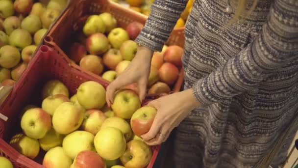 Руки женщины выбирая яблоко в фруктовом овощном супермаркете — стоковое видео