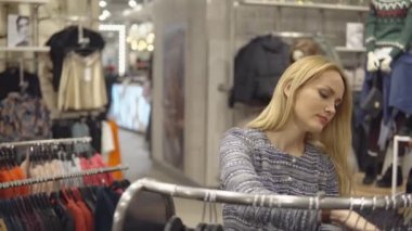 Giyim, dolap, moda, stil ve insanlar kavramı - mutlu sarışın kadın giyim mağaza seçimi