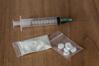 kaşık, plastik paket kokain ve ahşap masa üzerinde şırınga ile