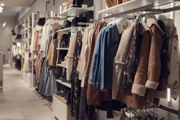 Vestidos de mujer y chaqueta en perchas en una tienda minorista . — Foto de Stock