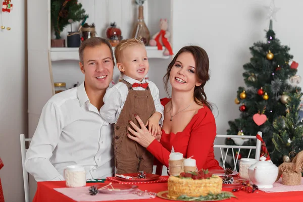 Feliz celebración familiar del Año Nuevo. La madre, el padre y el hijito sentados a la mesa . — Foto de Stock