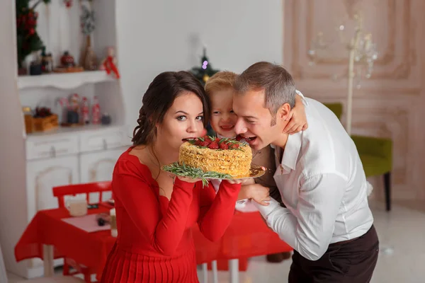 Família feliz mordida saboroso bolo de Natal na cozinha de fundo — Fotografia de Stock