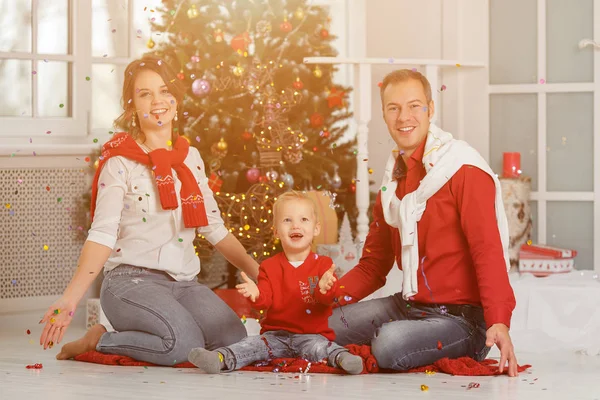 Glückliche Familie mit Konfetti auf dem Hintergrund des Weihnachtsbaums mit — Stockfoto