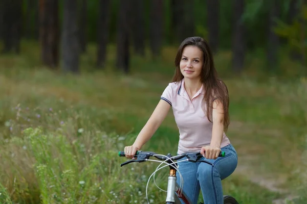 Jonge vrouw op fiets in het bos rijden — Stockfoto