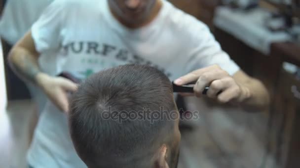 Master taglia capelli e barba di uomini nel barbiere, parrucchiere fa acconciatura per un giovane — Video Stock