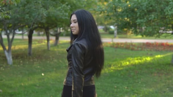 Genç güzel kız yürüyüş ve güneşli yaz park arka plan üzerinde etrafında döner — Stok video