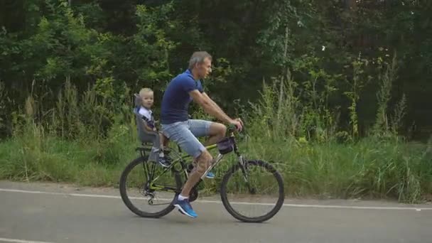 Far med son rider på cykel i skogen — Stockvideo