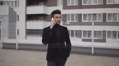 Yürüyüş ve şehrin cep telefonu konuşurken genç yakışıklı işadamı