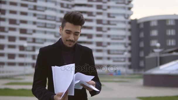 Счастливый молодой бизнесмен выбрасывает документы на улицу . — стоковое видео