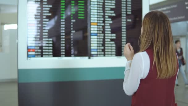 Belle fille se tient debout et vol de choix sur le fond du tableau de bord flou avec l'avis — Video