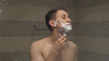 Genç adam aynanın önünde tıraş