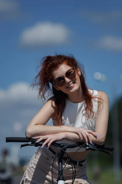 Красивая девушка в солнечных очках, наслаждающаяся теплой летней погодой, отдыхающая на велосипеде . — стоковое фото