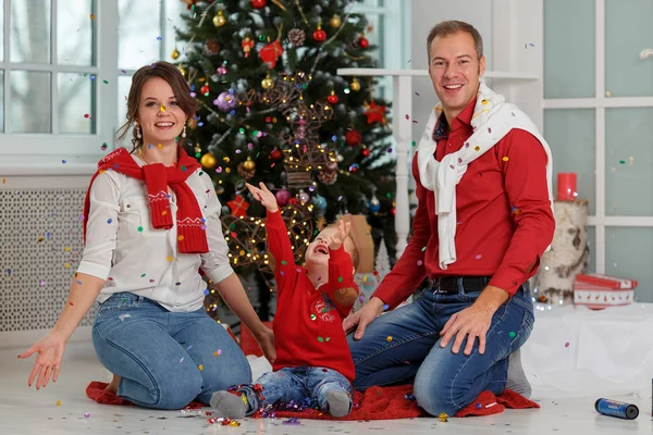 Família feliz com confete no fundo da árvore de Natal com presentes . — Fotografia de Stock