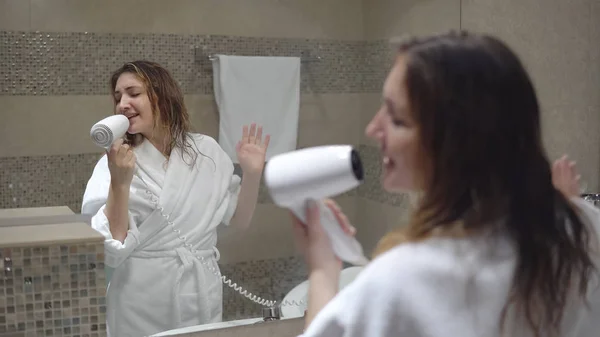 Mulher loira encantadora canta com secador de cabelo — Fotografia de Stock