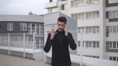 Smartphone üzerinde konuşmak ve gülümseyen mutlu giyen elbise açık havada çekip yakışıklı genç iş adamı